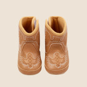 A tan pair of baby cowboy boots with white stitching.