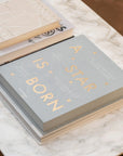 A light greyish blue photo album cover with text that reads, 'A Star Is Born'.