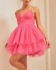 On a neutral background is a model wearing a hot pink tulle mini dress with a sweetheart neckline and thin straps.