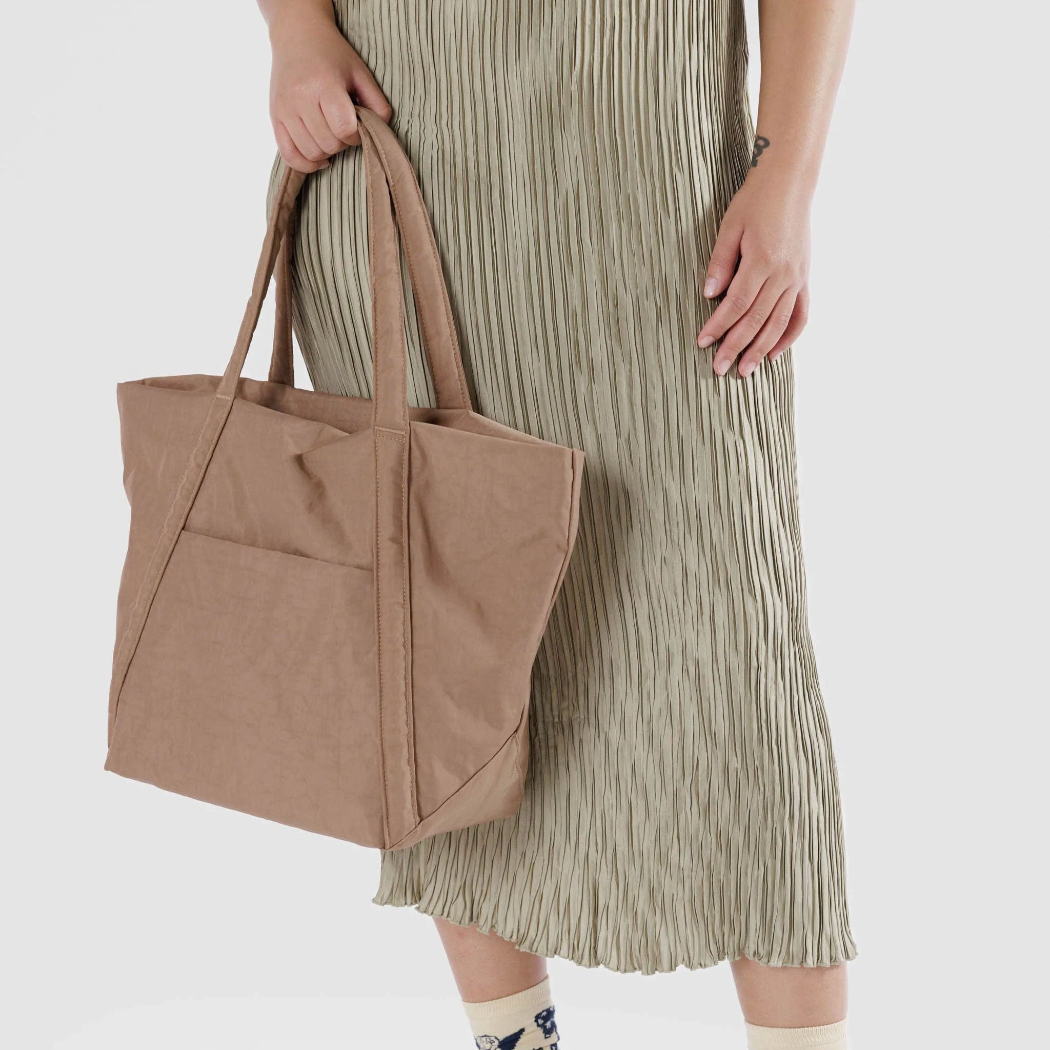 On a white background is a light brown nylon puffy tote bag with shoulder straps.