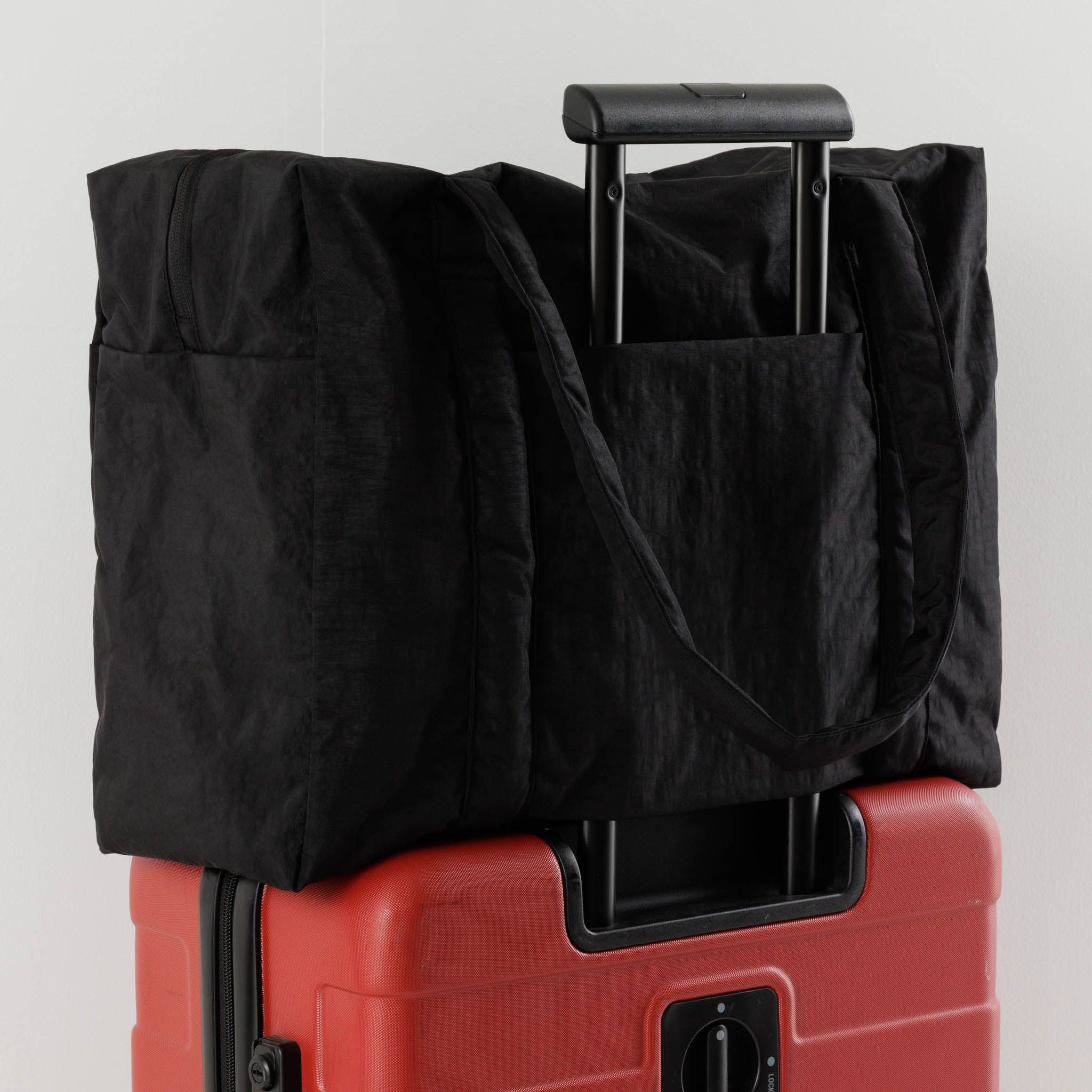 A black nylon bag sits on top of a suitcase
