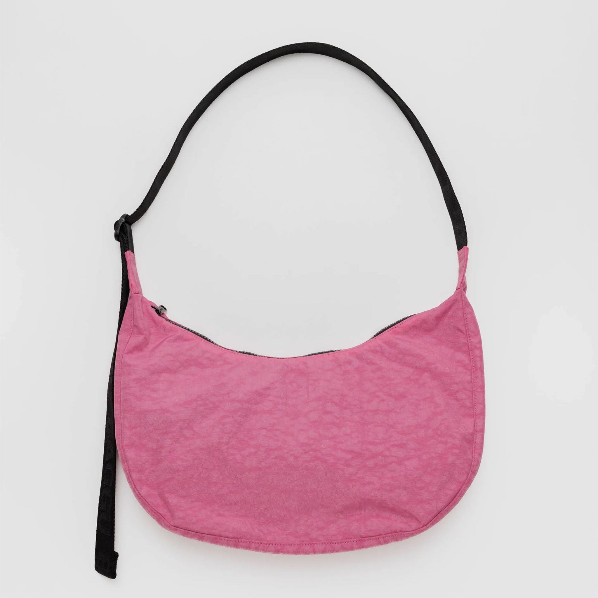 a bright pink crescent shaped bag with black strap