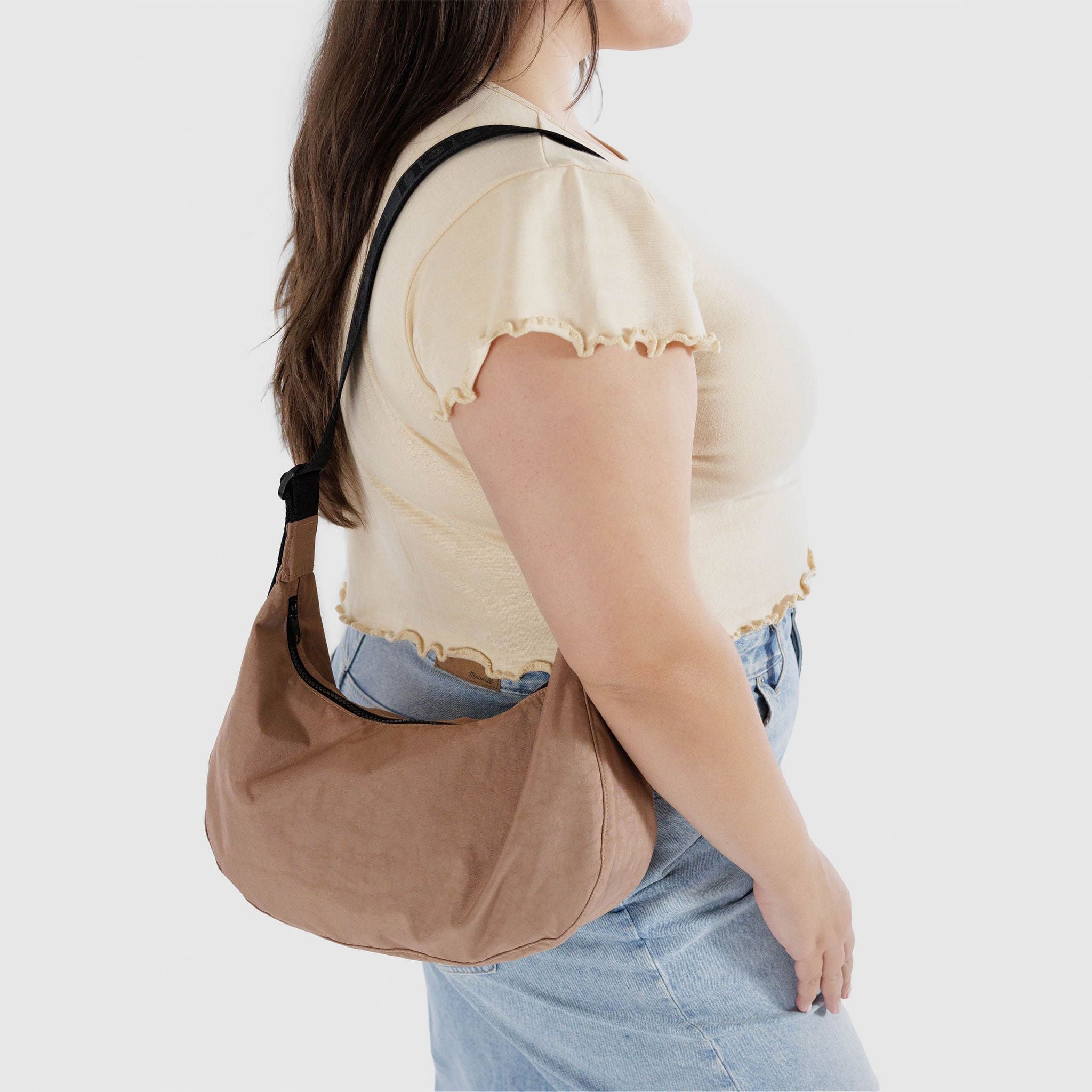 a light brown crescent shaped bag with black strap