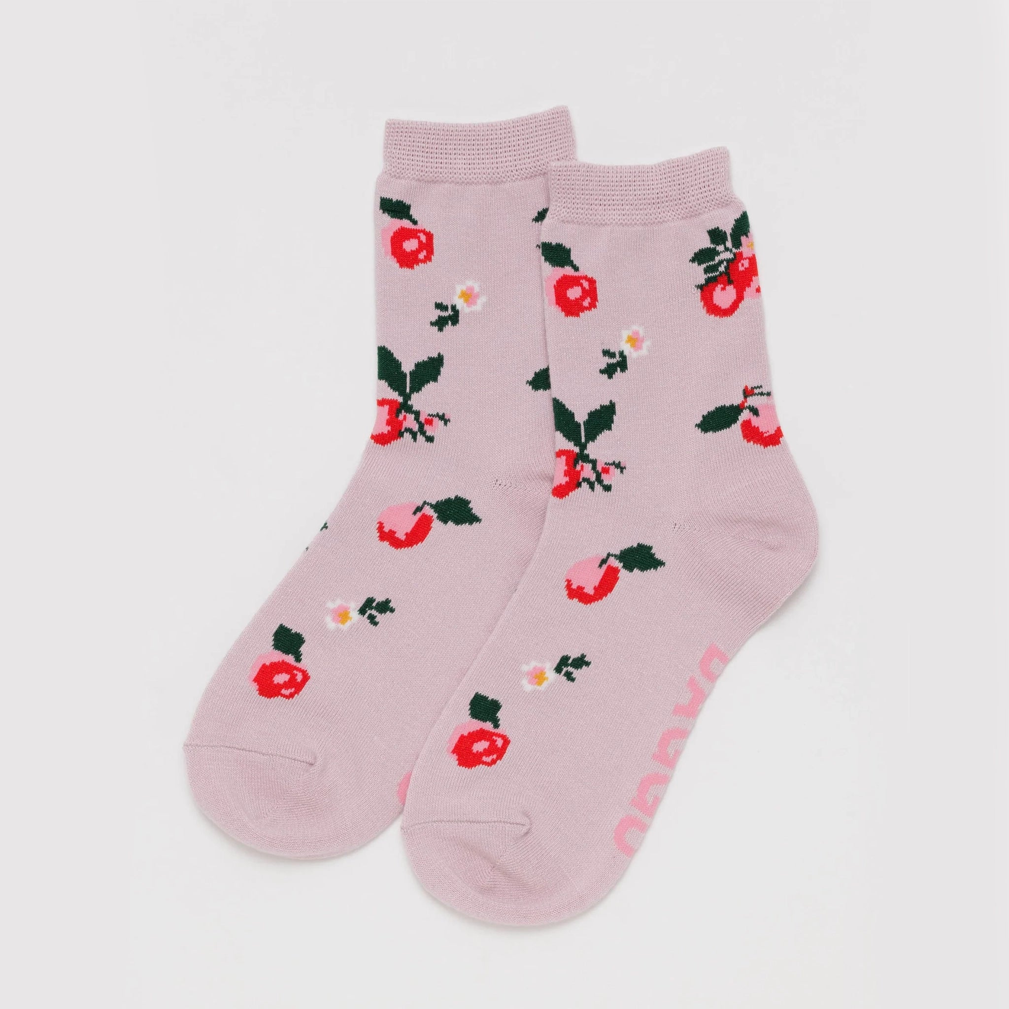 On a white background is a light pink pair of socks with an apple design. 