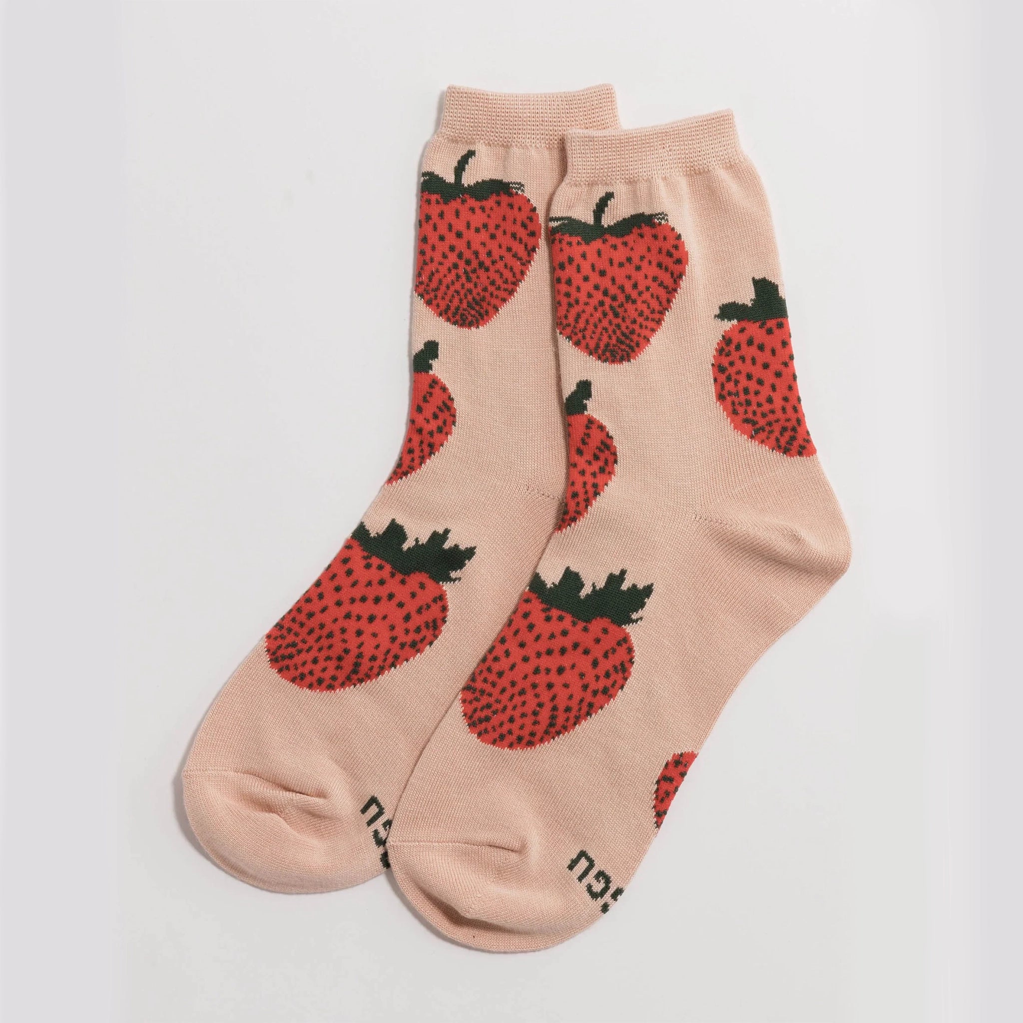 On a white background is a pair of pink crew socks with a red strawberry pattern on it.