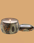 Round tin candle vessel and lid with dark and light gold floral pattern and white wax candle.