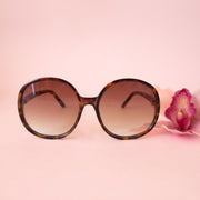 A cognac tortoise shaped round pair of sunglasses.