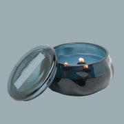 A dark blue glass jar candle with a lid and text that reads, 'Paddywax Rosewater Santal'.