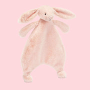 A blush pink bunny shaped furry unstuffed blanket/ toy.