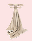 A beige blanket with a bunny head and arms on one corner.