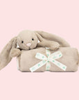 A beige blanket with a bunny head and arms on one corner.
