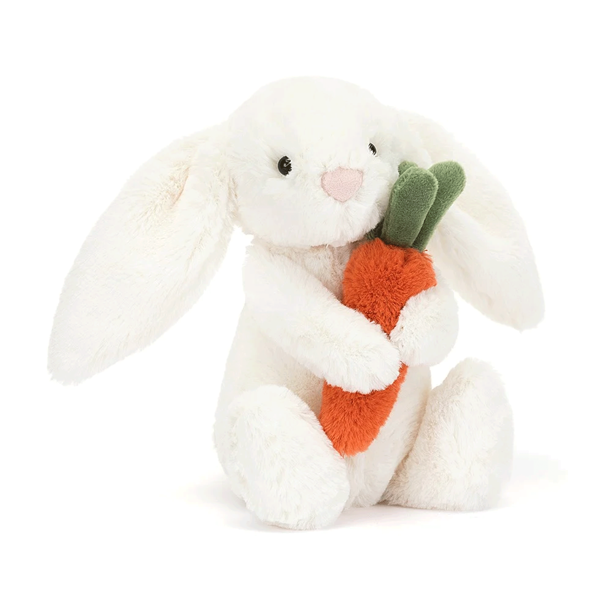 On a white background is a white stuffed toy bunny with long floppy ears and holding an orange stuffed toy carrot. 