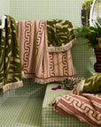 A green and ivory bamboo printed bath towel with tassel ends on both sides.