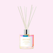 Irridescent glass oil diffuser on a soft pink background. The label on the incense diffuser reads, "Beach Vacay"