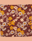 A yellow, rust and ivory floral print baby wrap blanket.