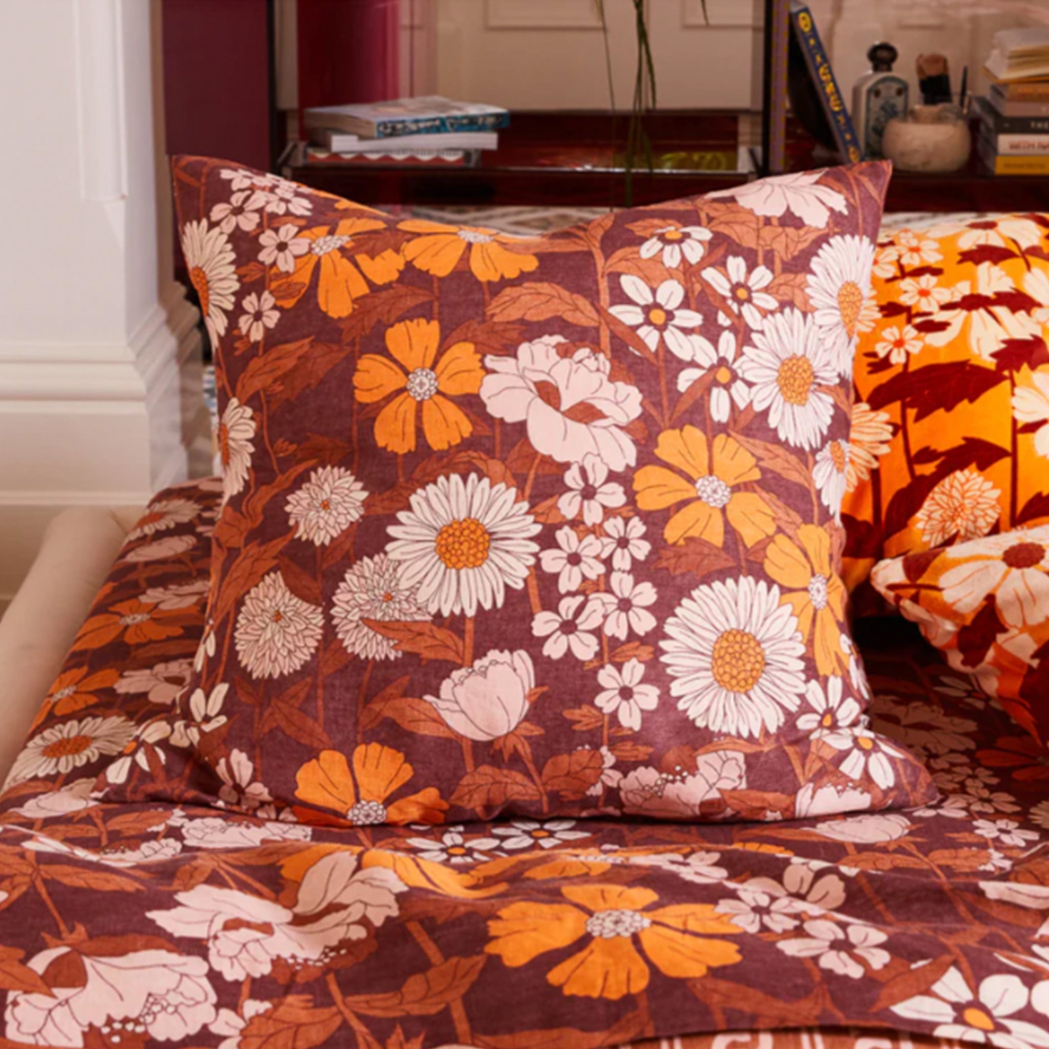 A euro pillowcase with a rust and orange floral print.