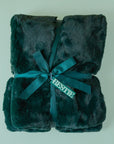 An emerald fur blanket with a satin ribbon and a mint tag that reads "bestie" tied onto it.