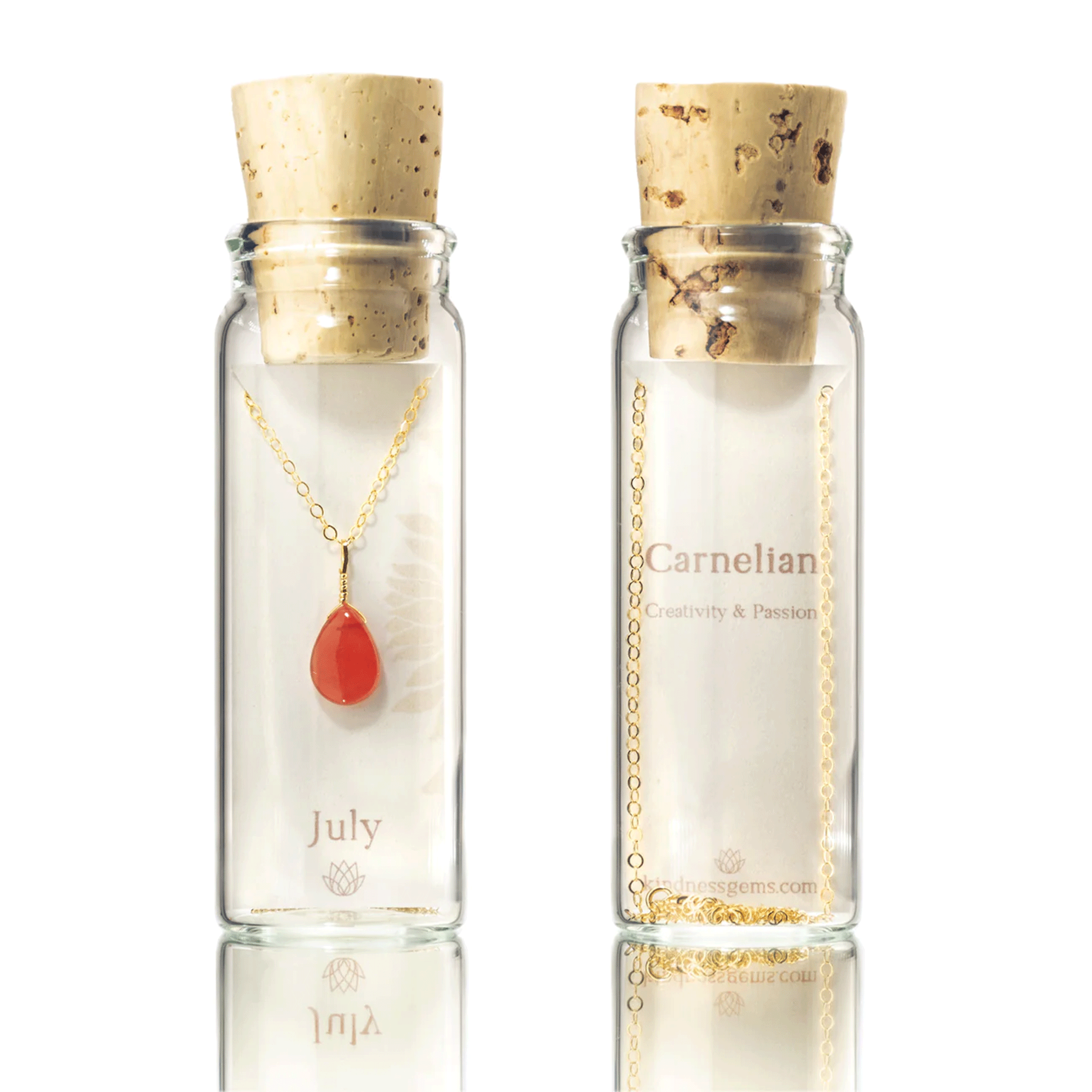 On a white background is a clear glass bottle with a cork top and filled with a gold chain necklace with a teardrop shaped carnelian July birthstone. 