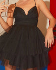 A model wearing a black mini dress with a sweatshirt shaped neckline, thin straps and a two layered tulle skirt.