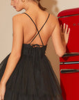 A model wearing a black mini dress with a sweatshirt shaped neckline, thin straps and a two layered tulle skirt.