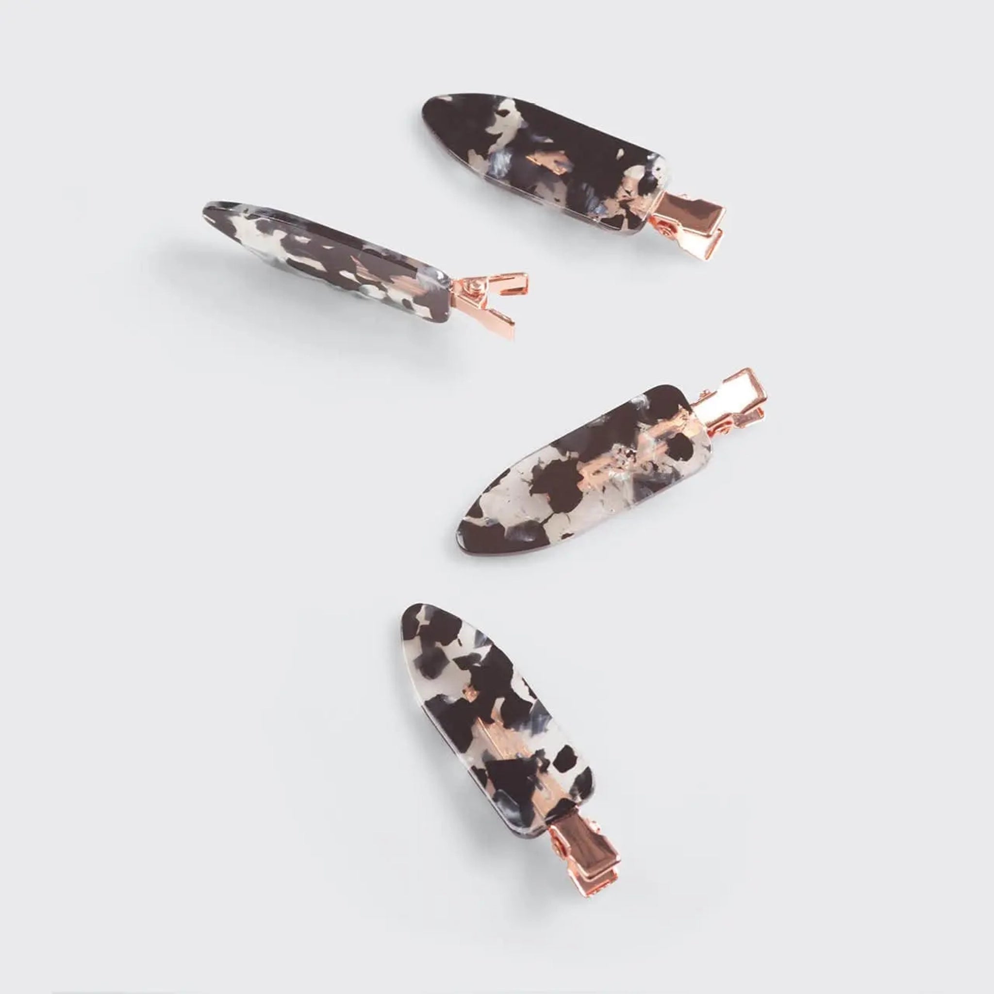 On a white background is four creaseless clips with a black terrazzo print.