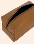 A warm brown vegan leather toiletry / cosmetic bag with a zipper closure and handle on one side.