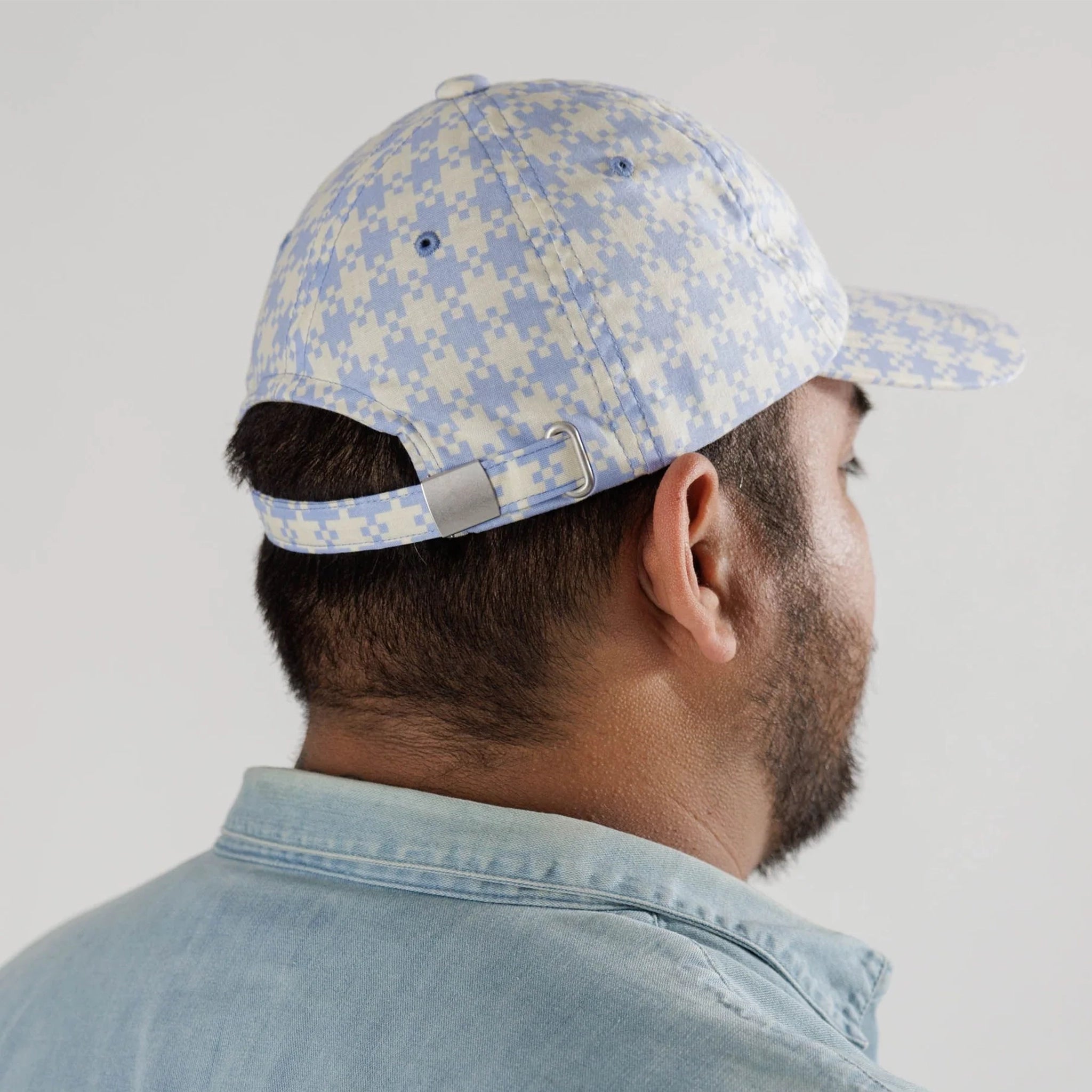 On a white background is a light blue and white gingham printed baseball hat.
