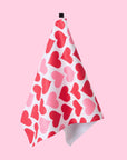 A one side printed waffle knit tea towel with a pink and red heart pattern.