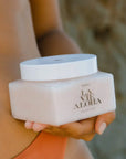 A clear container with a neutral body scrub inside, white lid and black text that reads, "La Vie Aloha".