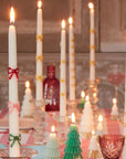 A set of two white taper candles with red, pink and green bow designs.
