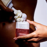 A white shimmery bottle of perfume with text that reads, 'Boy Smells Coco Cream'.