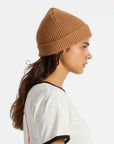 On a white background is a model wearing a tan ribbed beanie.