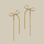 A pair of gold bow shaped earrings with dangles.