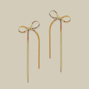 A pair of gold bow shaped earrings with dangles.