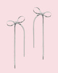 A silver pair of bow shaped earrings.