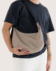 A brown and ivory striped crescent shaped bag with a black adjustable strap.
