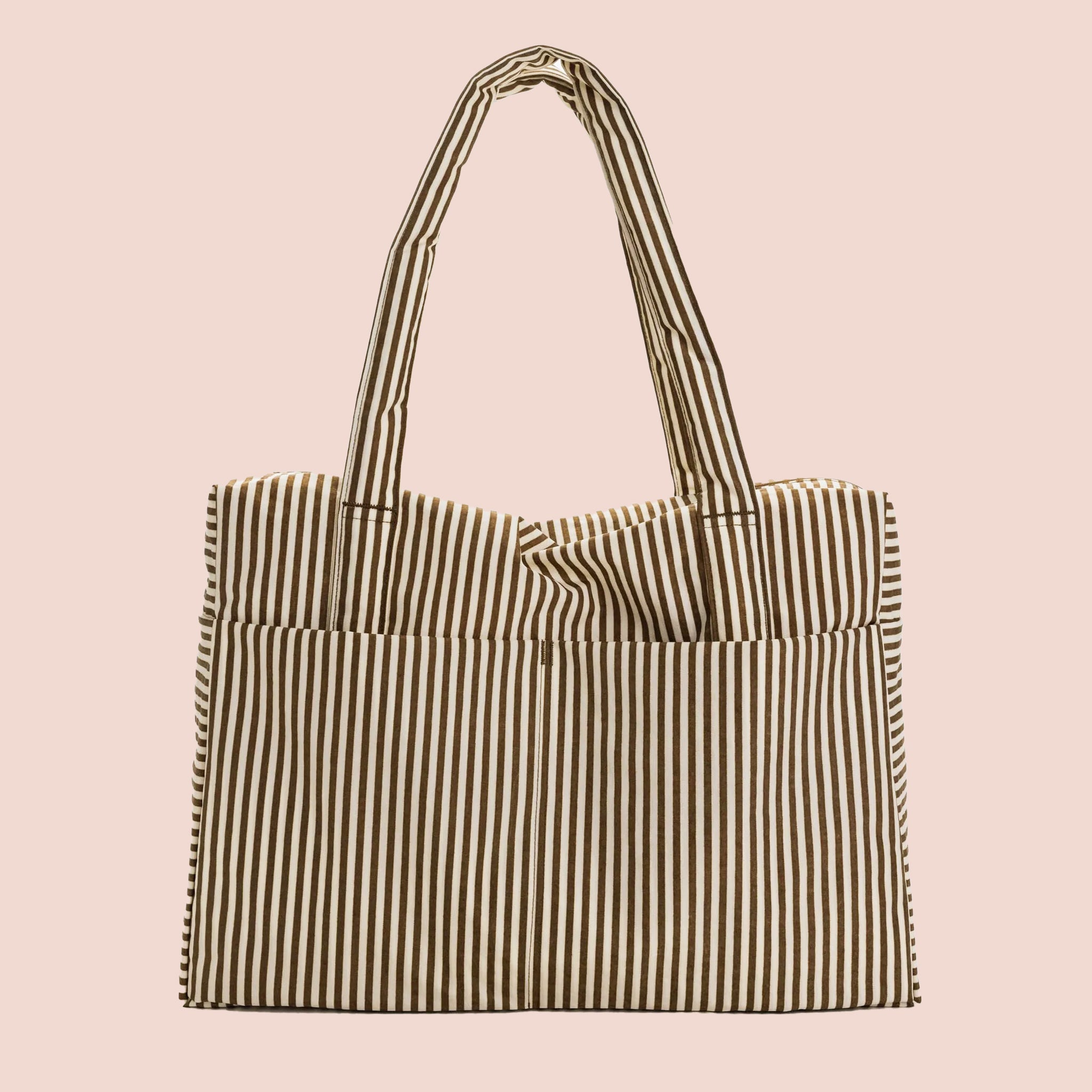On a light pink background is a brown and white striped travel bag tote.