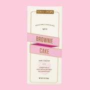 On a white background surrounded by chocolate and brownies is a neutral package filled with a chocolate bar and text on the front that reads, "Lolli & Pops Brownie Cake".