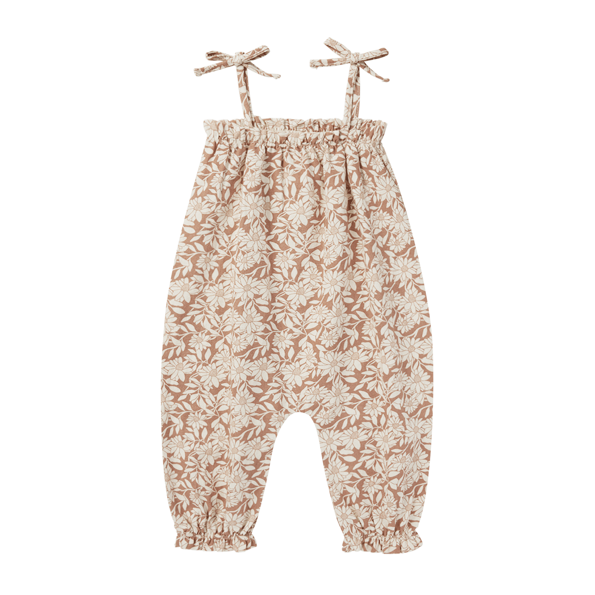 On a white background is a children&#39;s jumpsuit with a neutral floral print and shoulder tie strap details. 