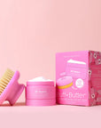 A body butter next to a pink dry brush.