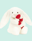 A white bunny shaped stuffed animal holding a red and white candy cane.