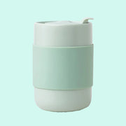 On a mint green background is a mint green ceramic tumbler with a silicone sleeve.