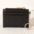 On a white background is a small black card case with a gold zipper and keychain. 