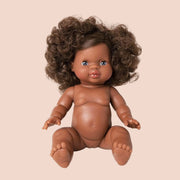 In front of a white background is a baby doll with dark brown curly hair.