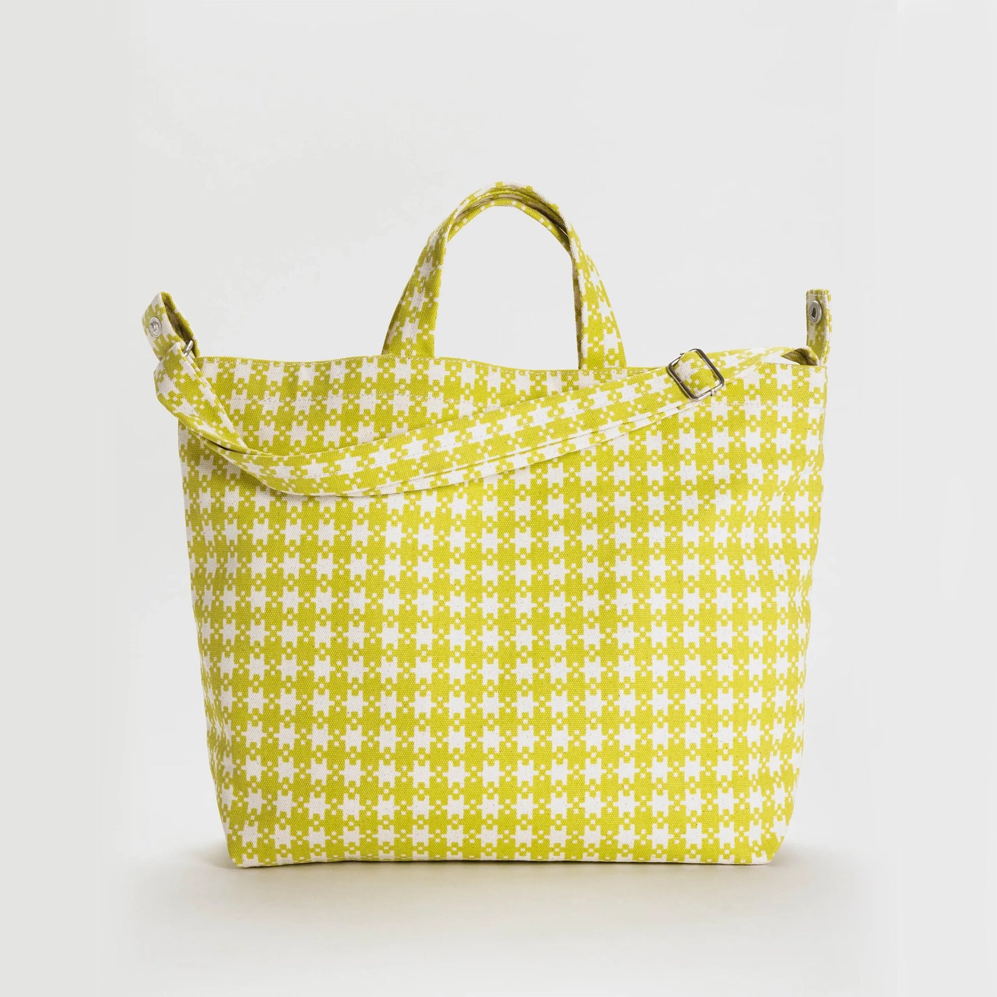 On a grey background is a neon green pixel gingham print tote bag with a shoulder strap and hand straps.