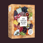 The front cover of box looks like a cheese board with an assortment of cheeses, meats and fruits along with a white square in the center that says, "The Cheese Board Deck".