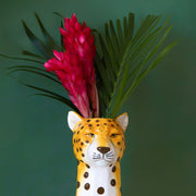 A cheetah head shaped ceramic vase with an opening at the top for an arrangement.
