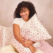 A light pink satin pillowcase with a cherry print.