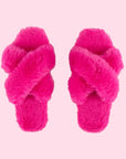 A pair of pink fuzzy slippers with a criss cross strap.
