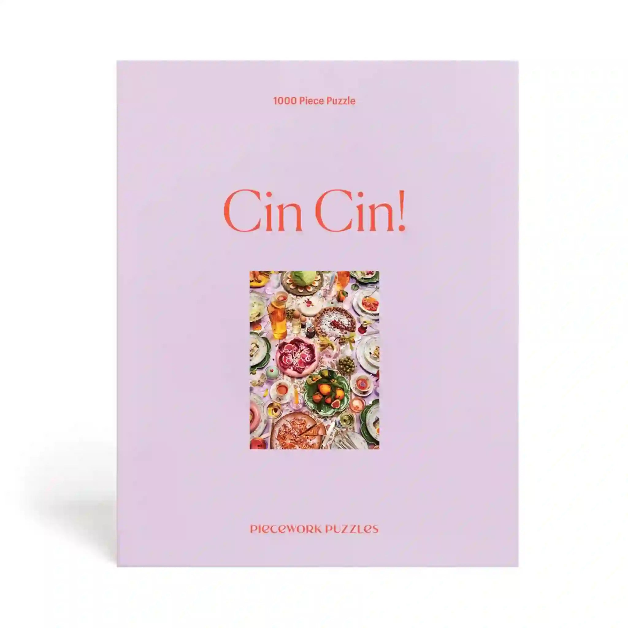 On a white background is a purple boxed puzzle with a colorful food and drink tablescape in the center along with orange text that reads, &quot;Cin! Cin!&quot;.